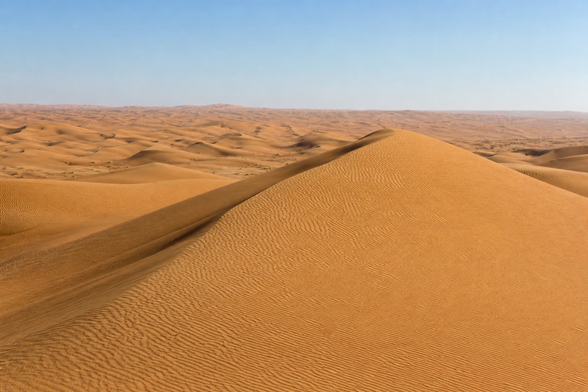 Golden dunes of the Wahiba Sands desert stretching toward the gateway at Al Wasil and Bidiyah