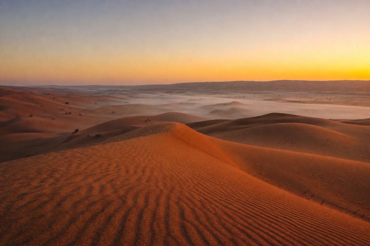 Sunrise light breaking over the crest of the Wahiba Sands dunes