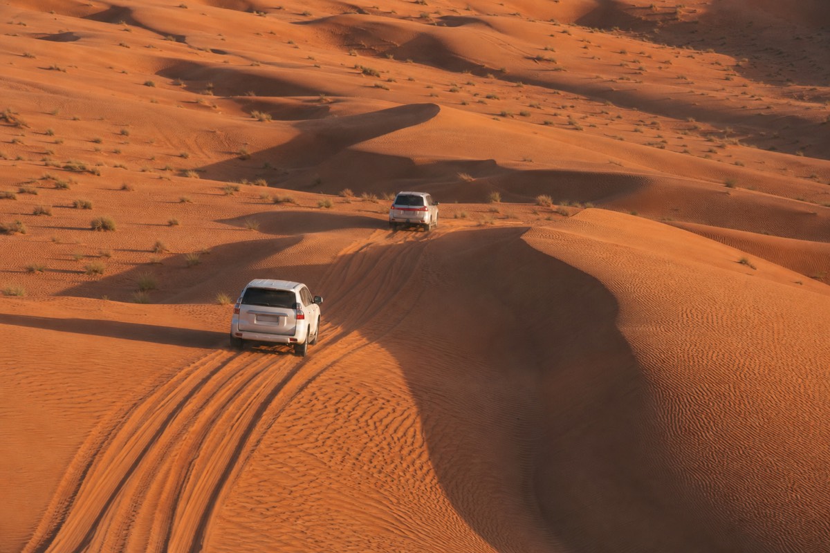 Four wheel drive vehicles convoying toward the dunes as part of getting to Wahiba Sands from Muscat